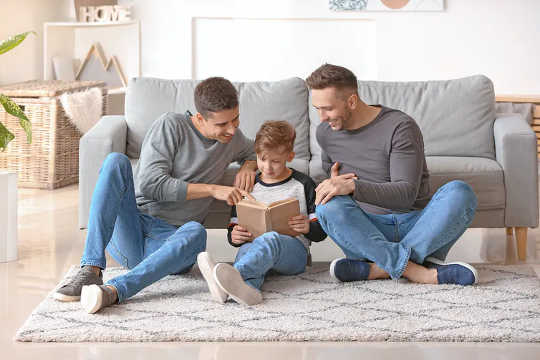 Two fathers reading with their son.