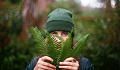 a young man holding some ferns and using them to hide behind